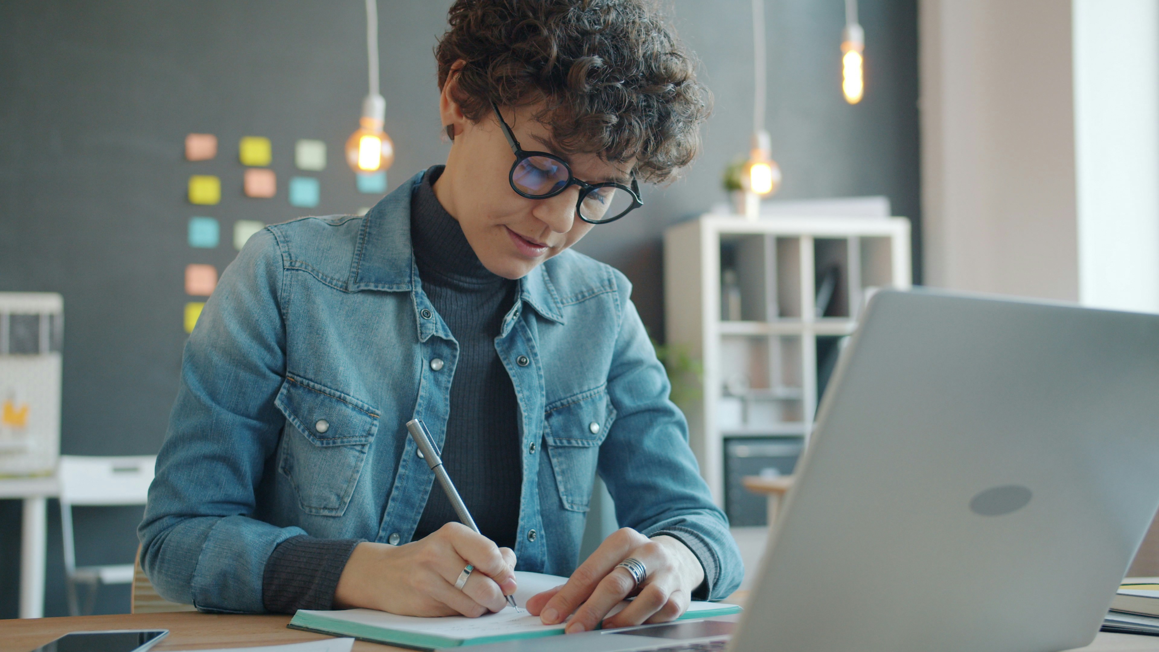 Woman with glasses writing in notebook